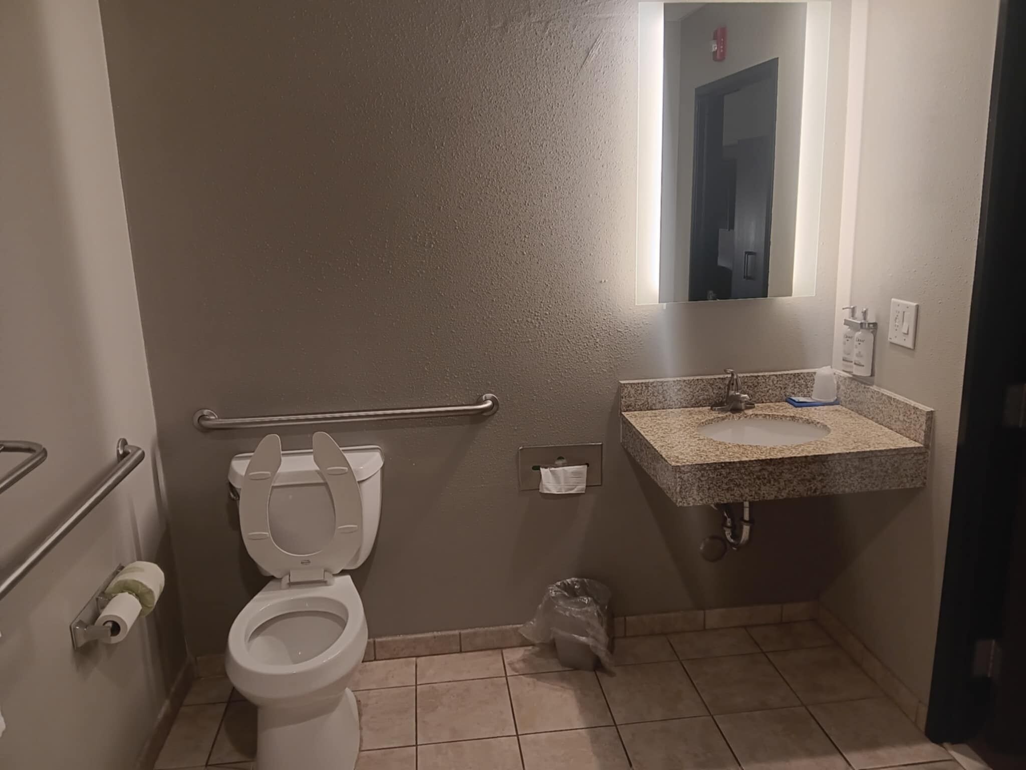 A small bathroom with a toilet, sink, and handrail.
