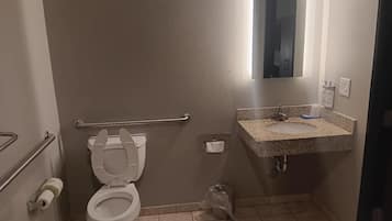 A small bathroom with a toilet, sink, and handrail.