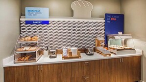 A bakery counter with various baked goods, a sign indicating breakfast is ready, and a display for how items are rolled. - Comfort Inn & Suites Miami - Route 66 (Miami)