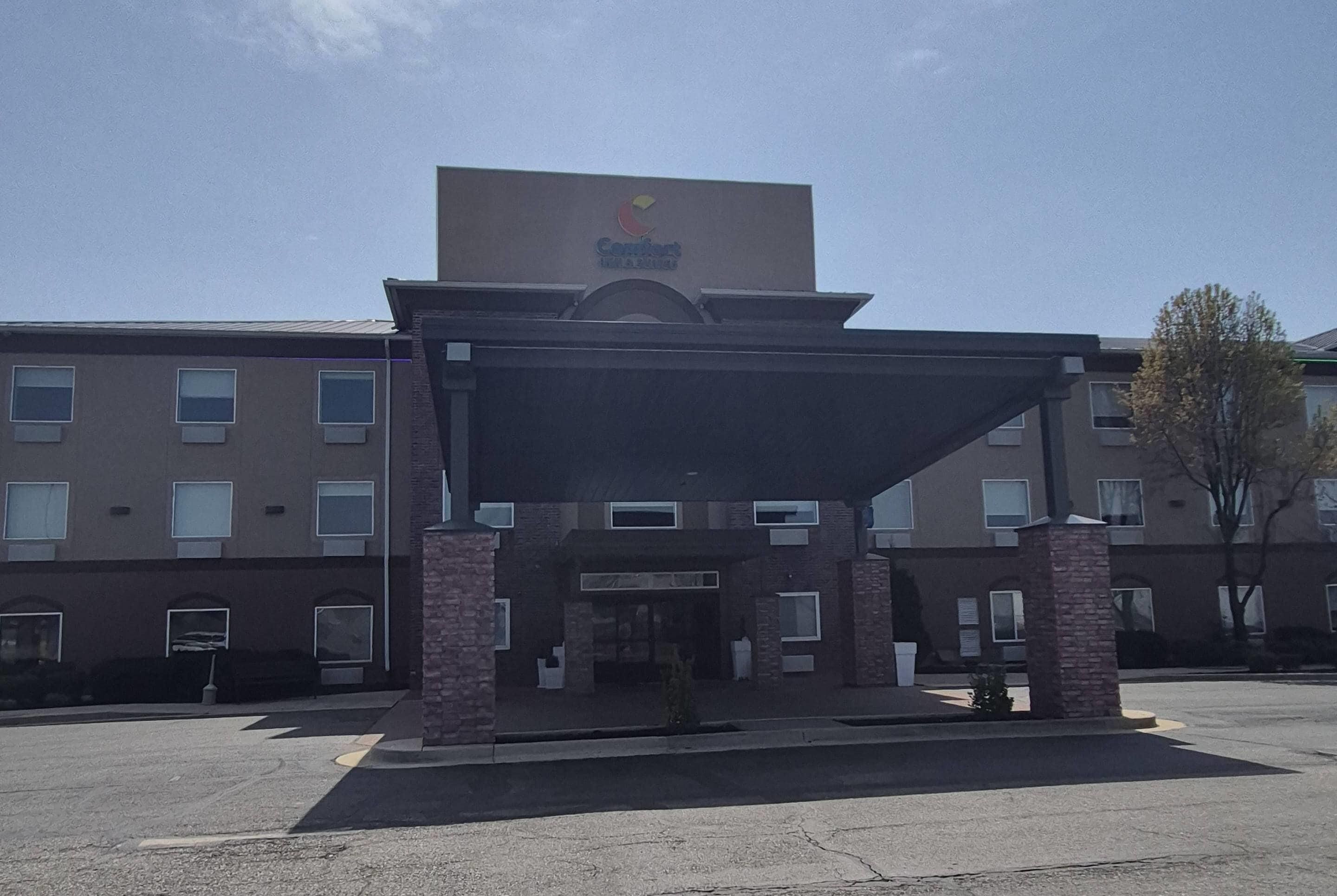 A hotel with a covered entrance, brick pillars, and a sign above the entrance.
