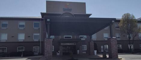 A hotel with a covered entrance, brick pillars, and a sign above the entrance.