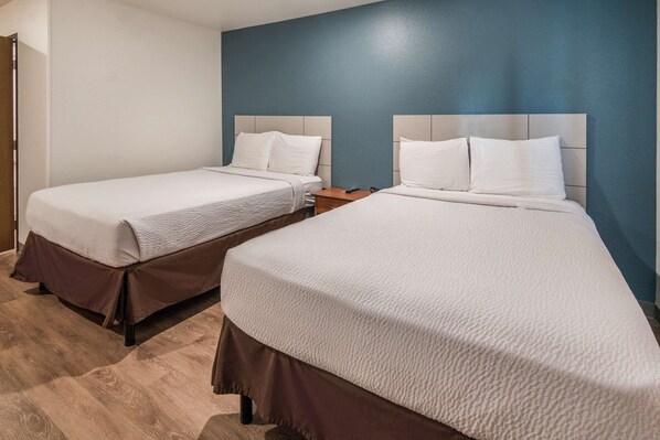 Two single beds with headboards, a wooden floor, and a blue accent wall.