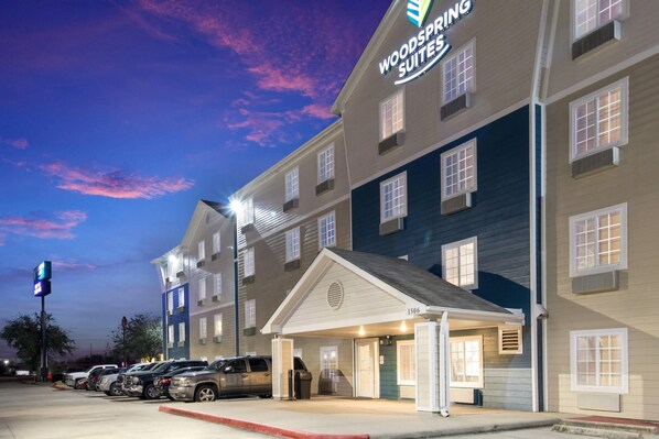 A hotel with a sign reading 'Woodspring Suites' and a covered entrance.