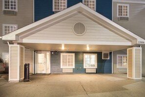 A building with a covered entrance, two windows with shutters, and a number '1506' on the right side. - WoodSpring Suites Houston La Porte (La Porte)
