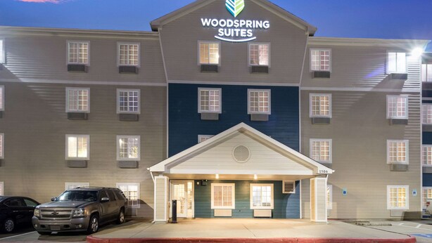 A multi-story hotel with a prominent 'Woodspring Suites' sign. - WoodSpring Suites Houston La Porte (La Porte)