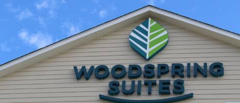 En bygning med et skilt, der viser "WOODSPRING SUITES".