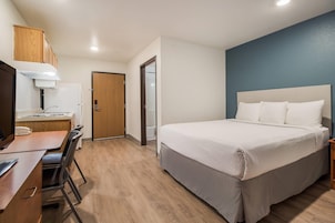 Habitación de hotel con cama, escritorio con silla, teléfono y puerta que da a un baño.