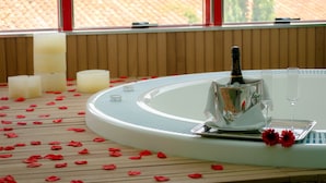 A spa area with a bathtub, candles, and rose petals on the floor. - Hotel 4* Mirador de Llerena (Llerena)