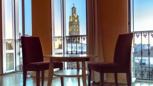 A room with a large window, two red chairs, and a wooden table. - Hotel 4* Mirador de Llerena (Llerena)