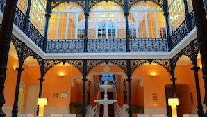 A grand lobby with a central fountain, ornate black railings, and a staircase leading to an upper level. - Hotel 4* Mirador de Llerena (Llerena)