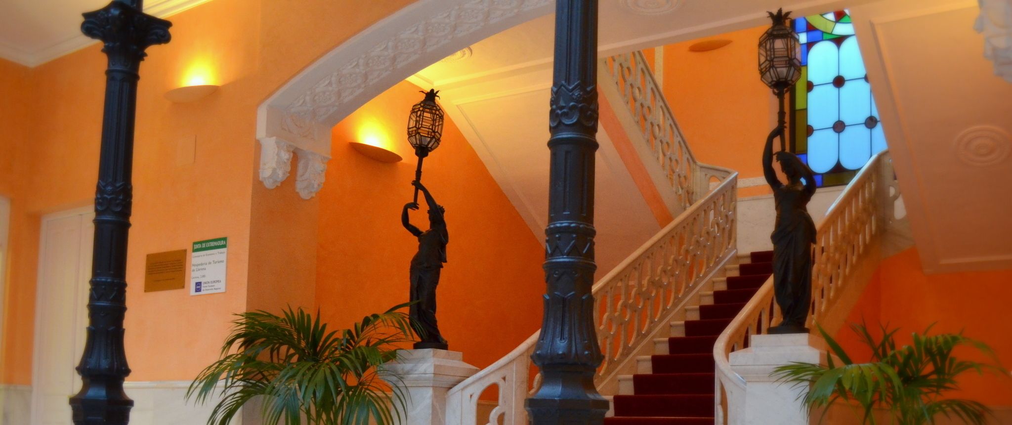 A grand staircase with ornate black balusters, a white balustrade, and a stained glass window.