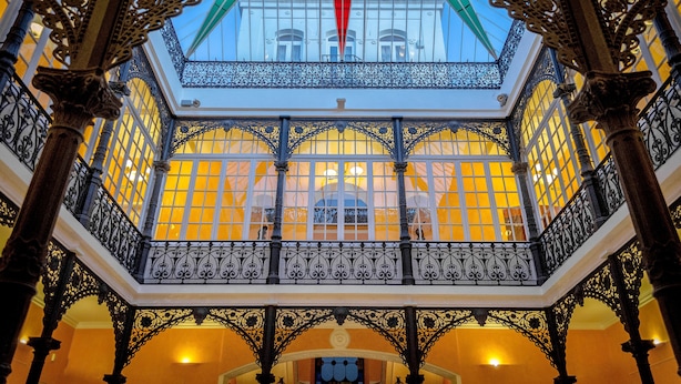 A grand interior with ornate iron railings and a skylight. - Hotel 4* Mirador de Llerena (Llerena)