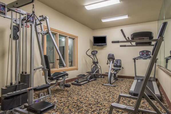 A gym with various exercise equipment, a television, and a patterned floor. - Baymont by Wyndham Wichita Falls (Wichita Falls)