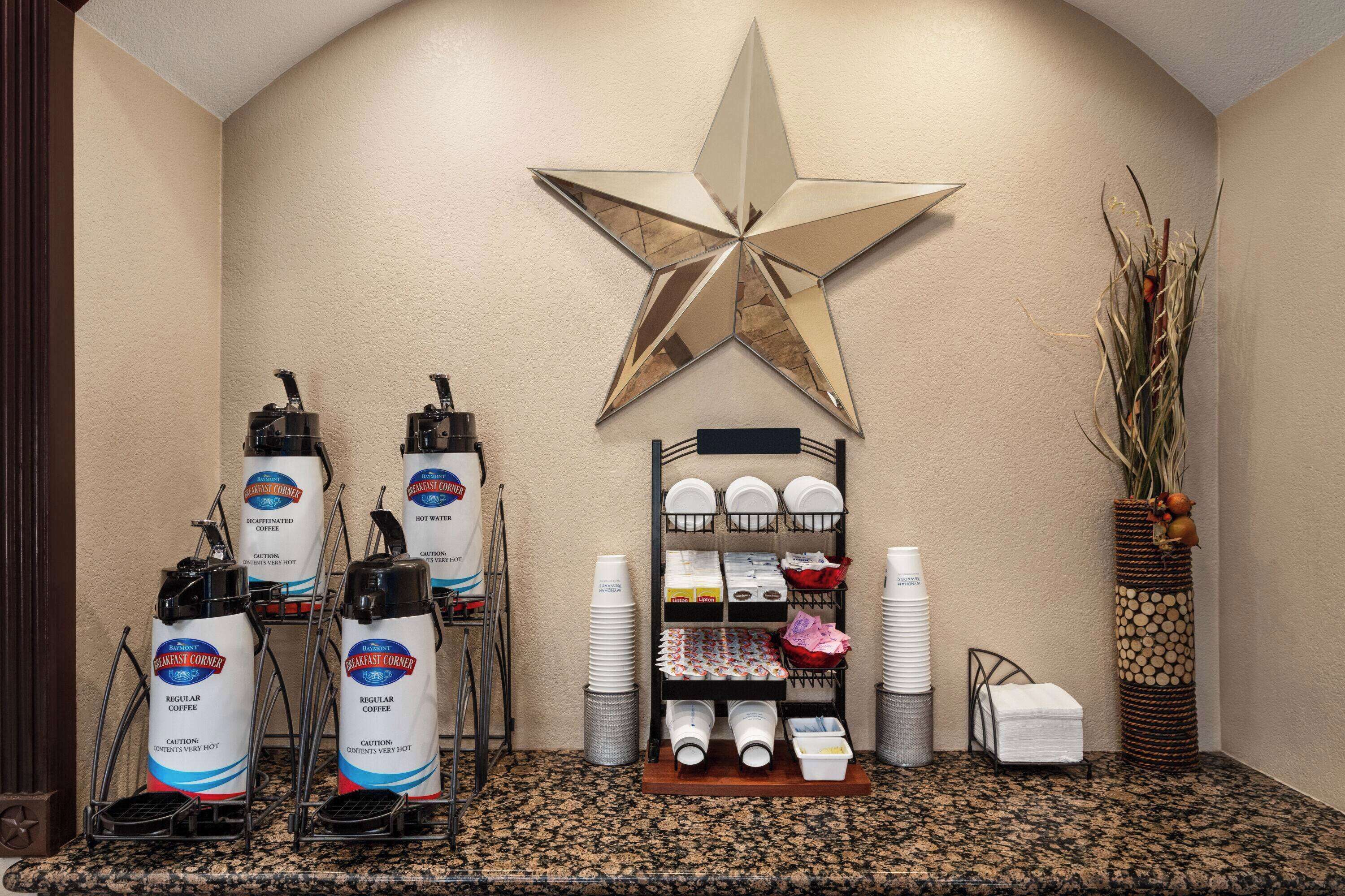 Una estación de desayuno con dispensadores de café, un escurreplatos y una estrella decorativa en la pared.