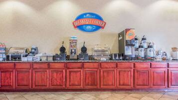 A breakfast counter with a Baymont Breakfast Corner sign, coffee machines, and various food items.