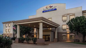 Un hotel con entrada cubierta, una bandera estadounidense y un letrero que dice "Baymont by Wyndham".
