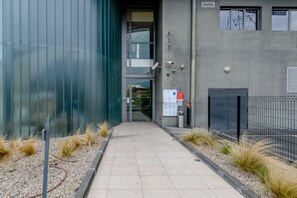 Une entrée moderne avec une porte en verre, une clôture en métal et un chemin de gravier.