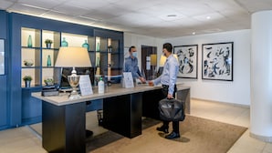 A reception desk with a blue wall, a lamp, and framed artwork.