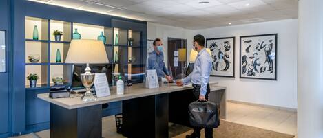 A reception desk with a blue wall, a lamp, and framed artwork.