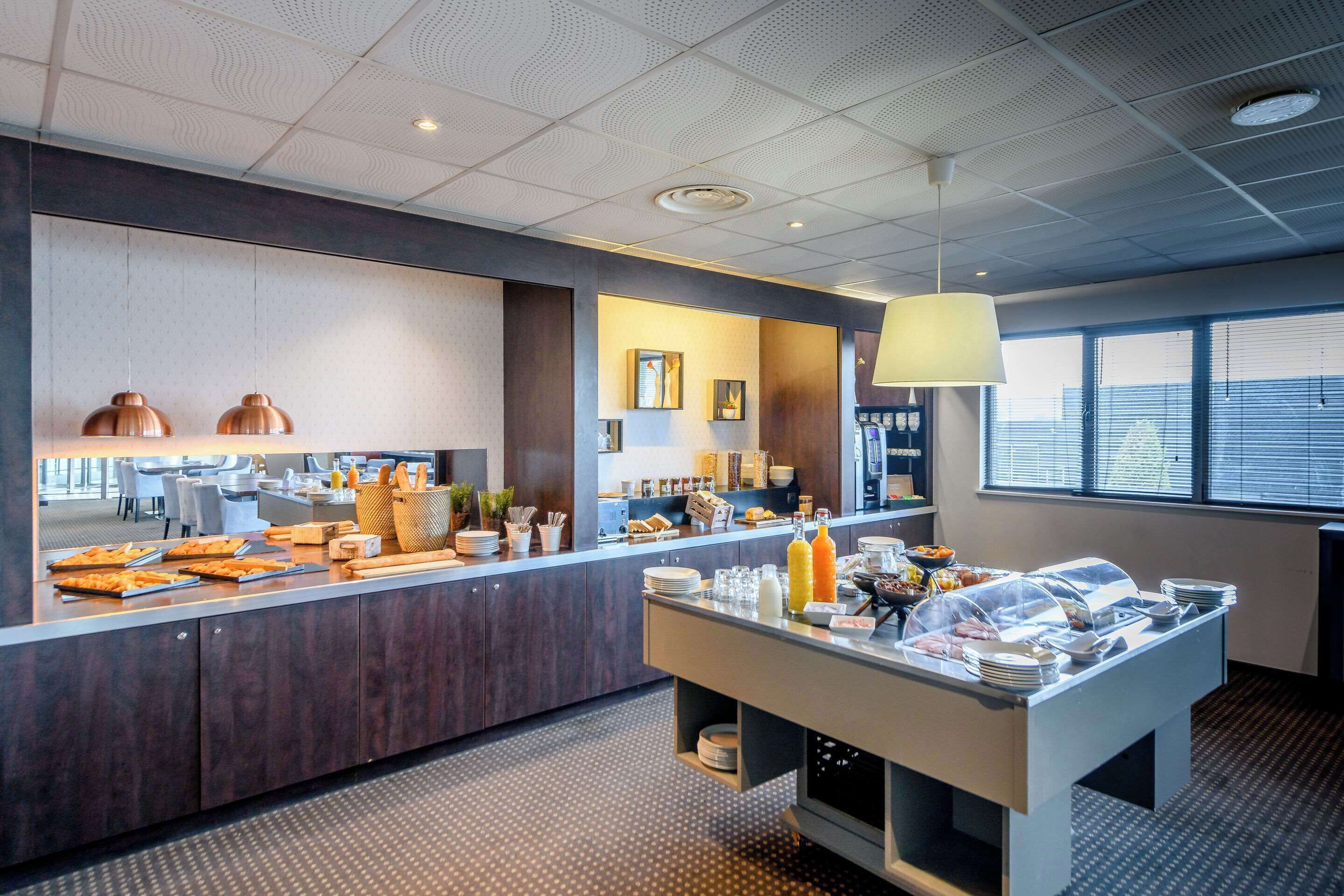 Un área de desayuno de hotel moderna con mostrador, bufé y zona de estar.