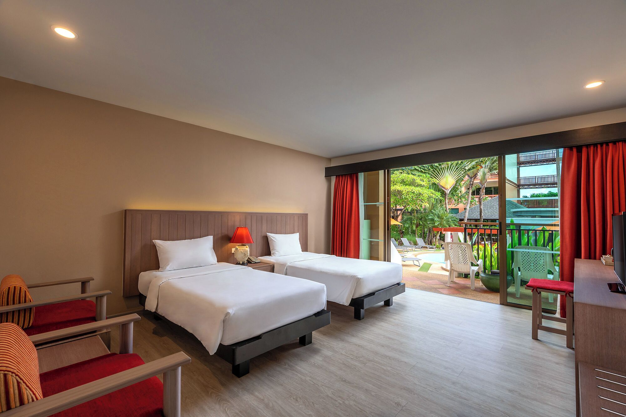 Habitación de hotel con dos camas, un escritorio, una silla y vistas a un jardín y una piscina.