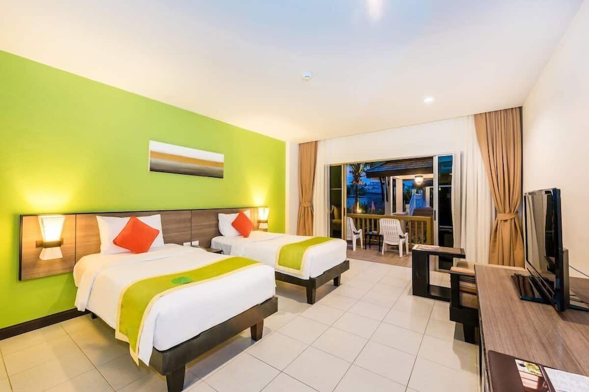 Een hotelkamer met twee bedden, een televisie en een balkon met uitzicht.