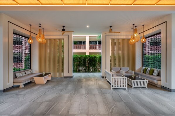 A spacious lobby with a modern design, featuring a central seating area with sofas and a coffee table, flanked by tall, decorative light fixtures. - Kata Sea Breeze Resort (Karon)