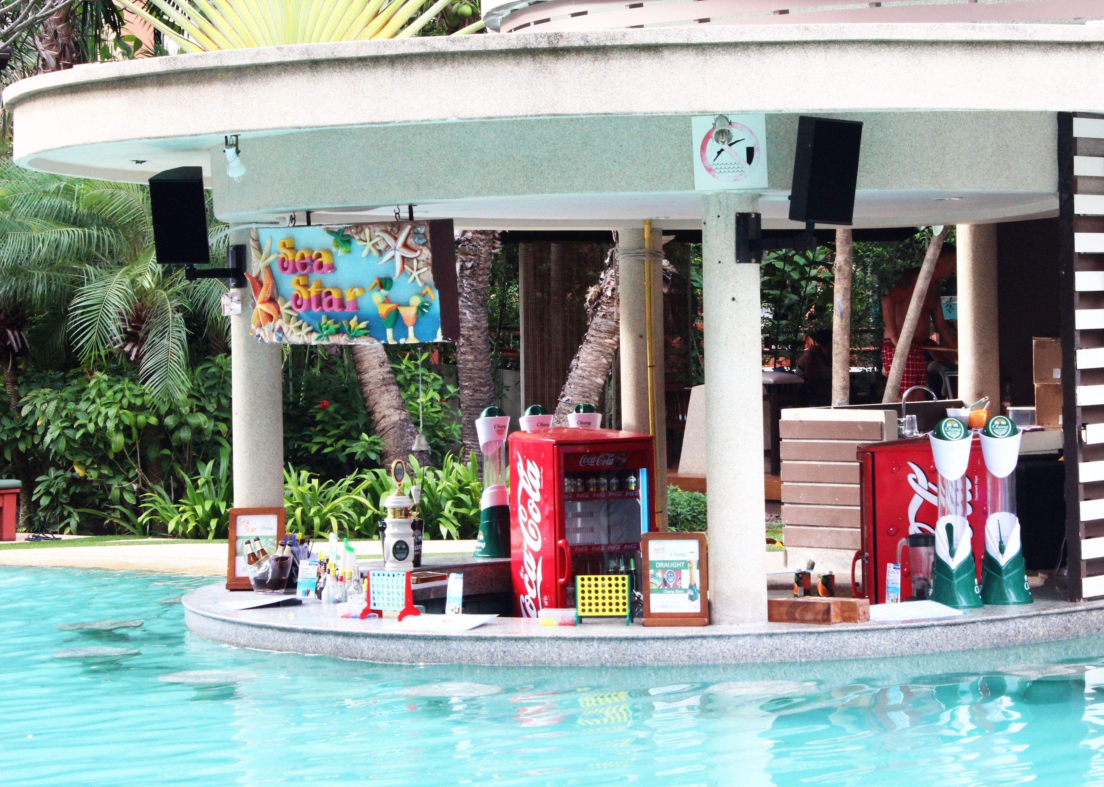 A poolside bar area with a Coca-Cola vending machine, a Draught beer machine, and a sign reading "Sea Star".