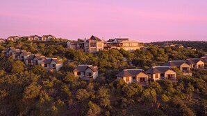 A residential area with multiple houses on a hillside, surrounded by dense vegetation. - Kuzuko Lodge (Blue Crane Route)
