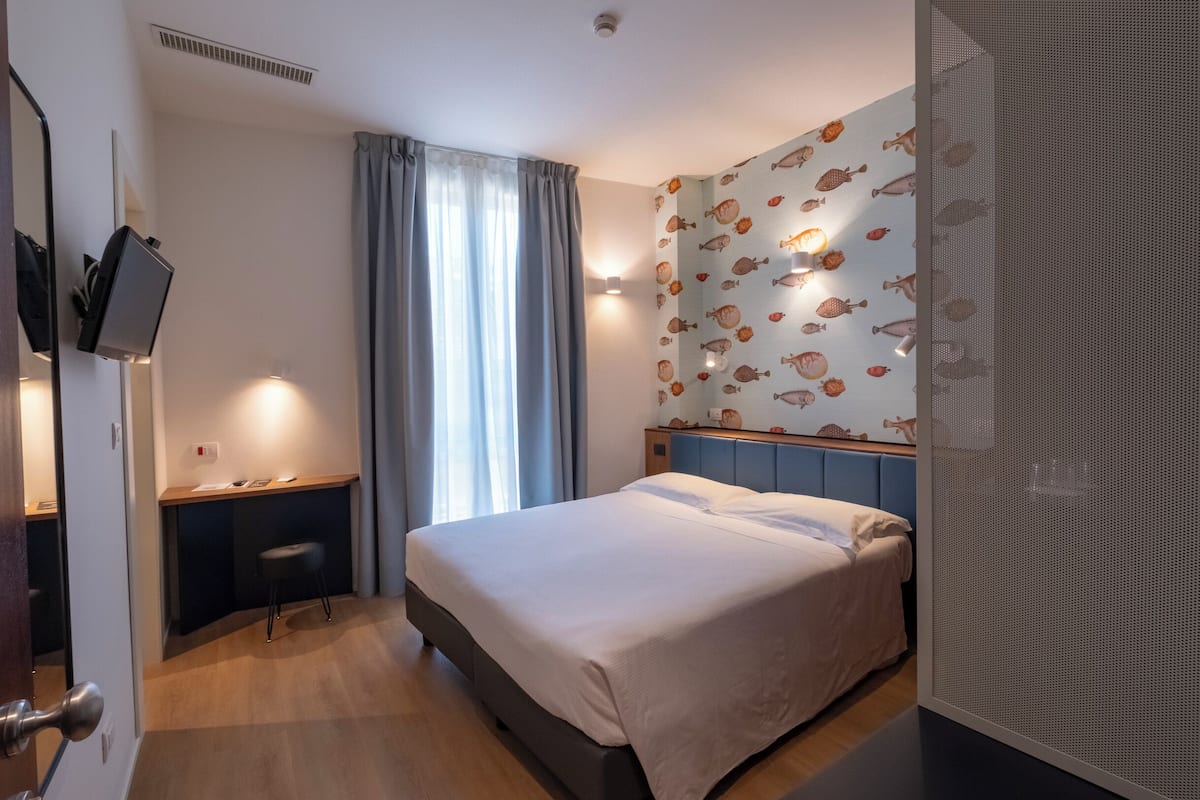 Une chambre d’hôtel avec un lit, un bureau et une chaise.