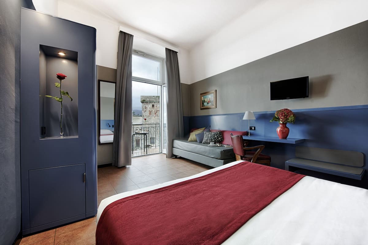 Une chambre d’hôtel moderne équipée d’un lit, d’un bureau, d’une chaise, d’une télévision et d’un balcon avec vue.