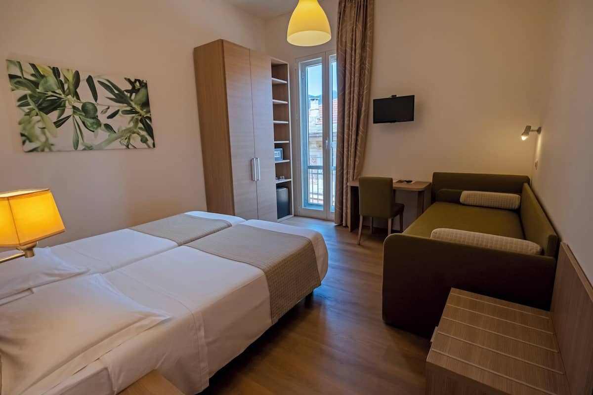 Een hotelkamer met een bed, een bank, een bureau, een televisie en een garderobe.