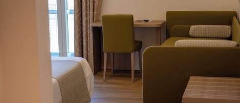 Ein Zimmer mit einem Bett, einem Schreibtisch, einem Sessel und einer Couch.