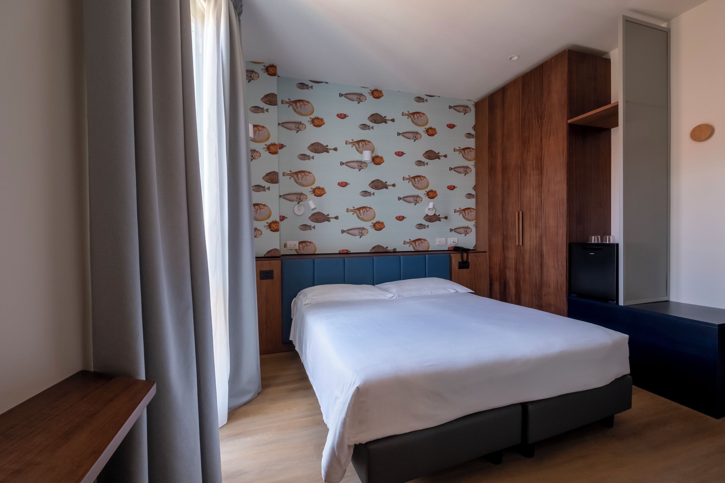 A hotel room with a bed, a wooden headboard, a wardrobe, and a TV.