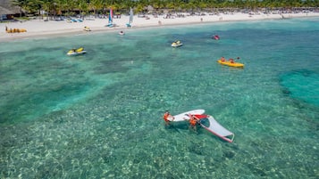 Une plage à l’eau turquoise et limpide, un rivage sablonneux et plusieurs bateaux.