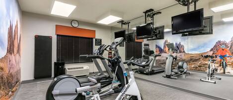 Ein Fitnessstudio mit Ergometer, Laufbändern und einer Spiegelwand.