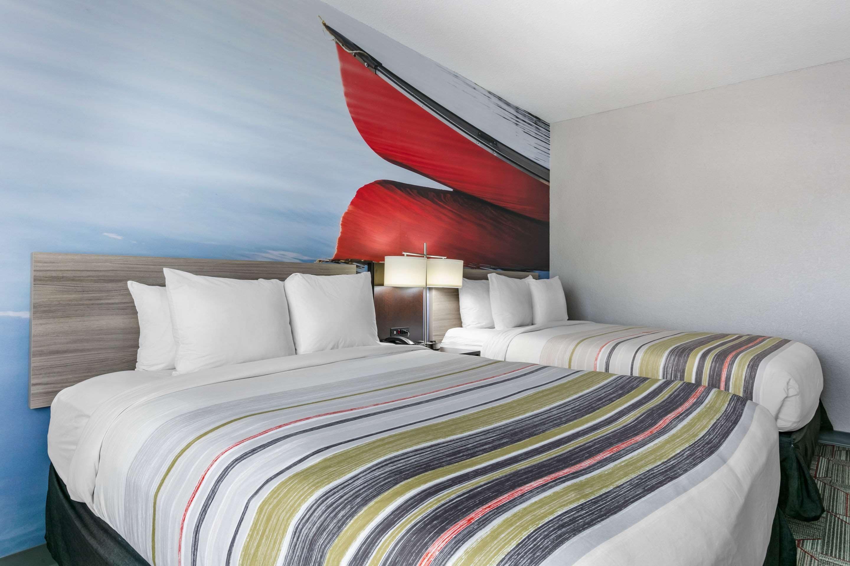 A hotel room with a large bed, two bedside tables, a nightstand, and a wall-mounted lamp.