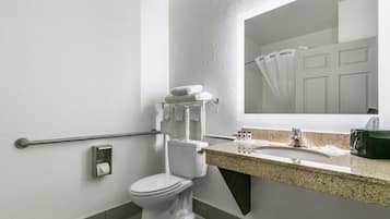 A modern bathroom with a toilet, hand dryer, towel rack, sink, and a mirror.