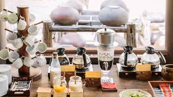 A coffee station with various brewing equipment and labeled containers of milk and sugar.