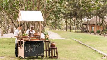 A food cart with a chalkboard sign, surrounded by trees and a pathway.