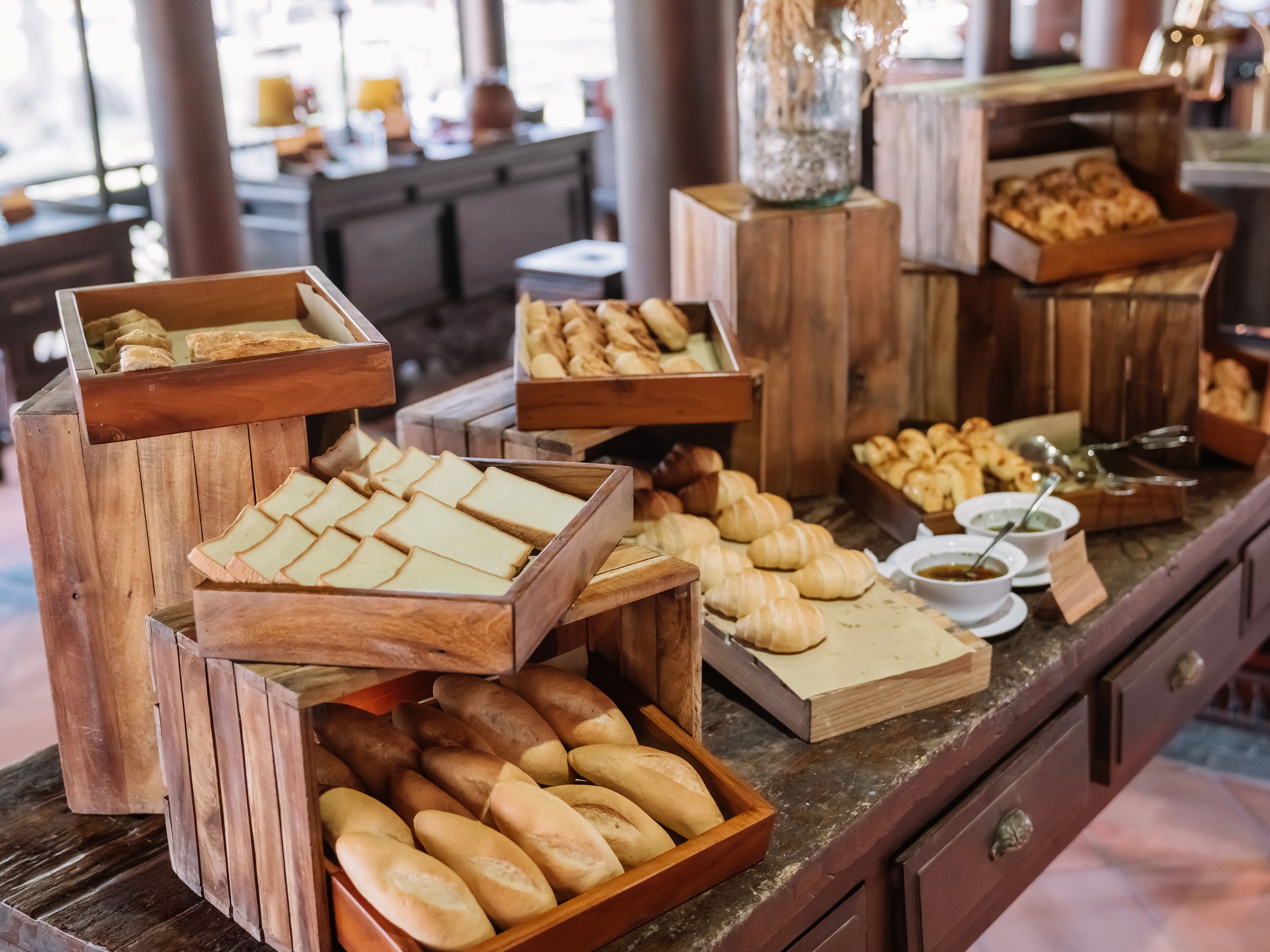Ein Buffet mit verschiedenen Brotsorten und Gebäck, präsentiert in Holzkästen.