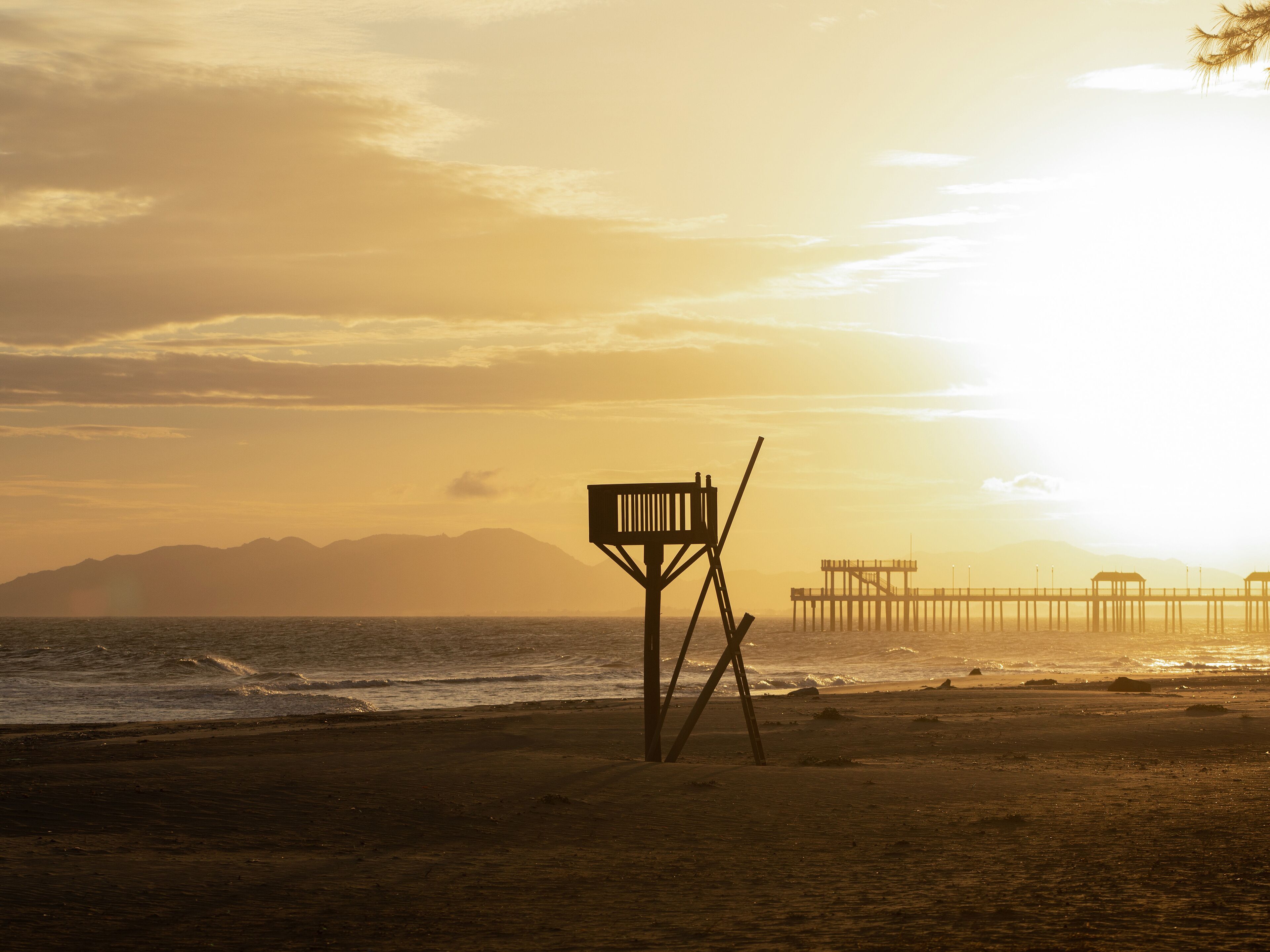 A beach with a wooden structure and a pier extending into the water.