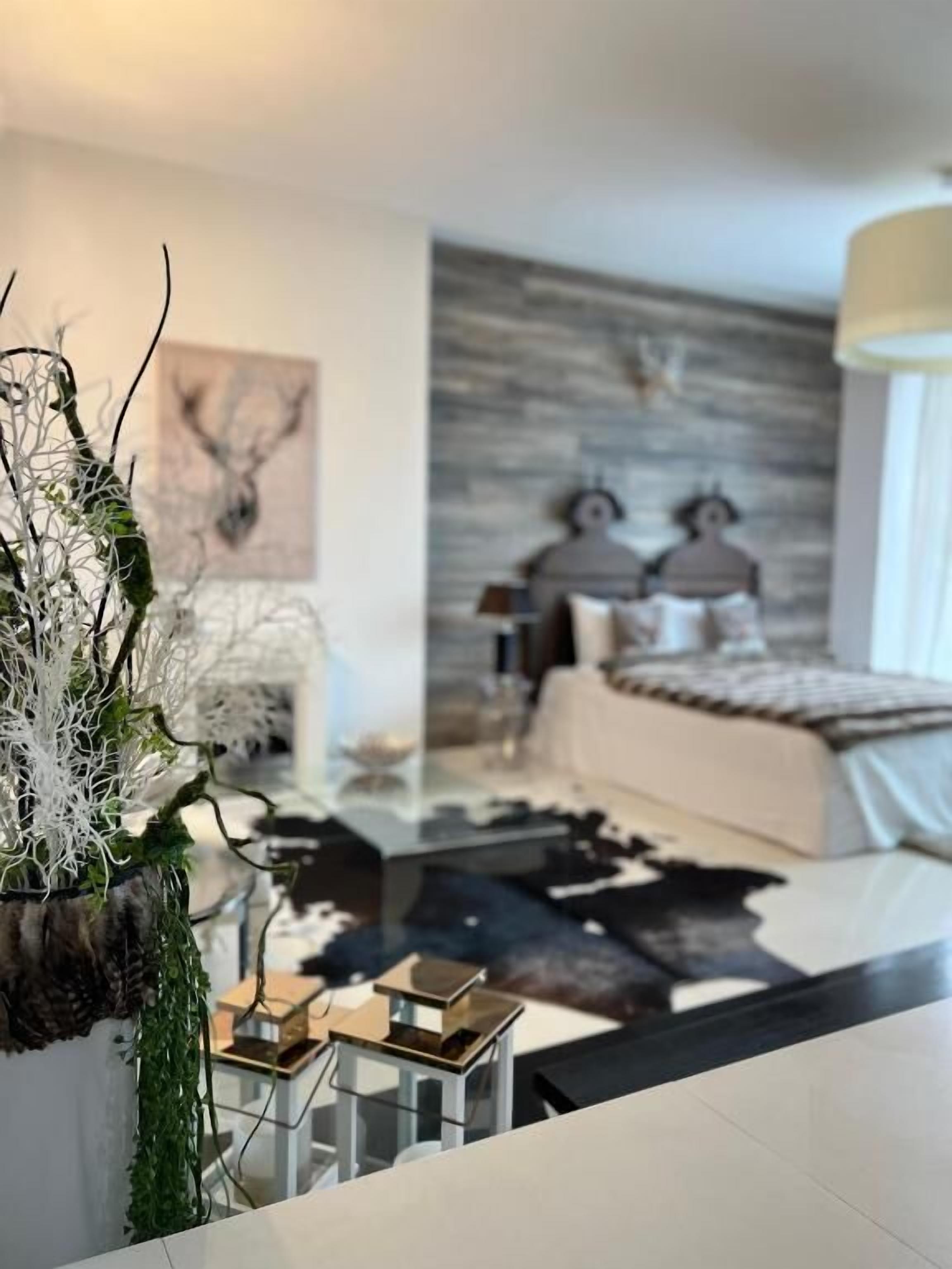 A modern bedroom with a bed, a nightstand, and a decorative plant.