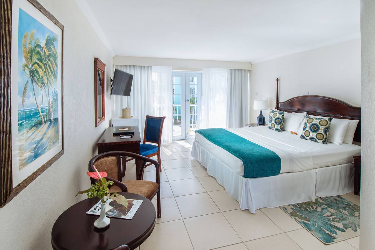 Ein Hotelzimmer mit einem Bett, einem Schreibtisch, einem Sessel, einem Fernseher und einem Gemälde.