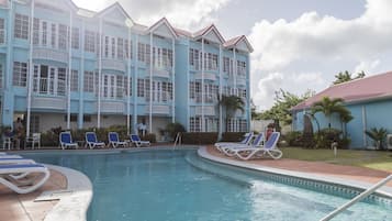Un hôtel doté d’une piscine, de plusieurs balcons et de chaises longues.