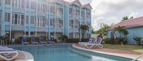 Un hôtel doté d’une piscine, de plusieurs balcons et de chaises longues.
