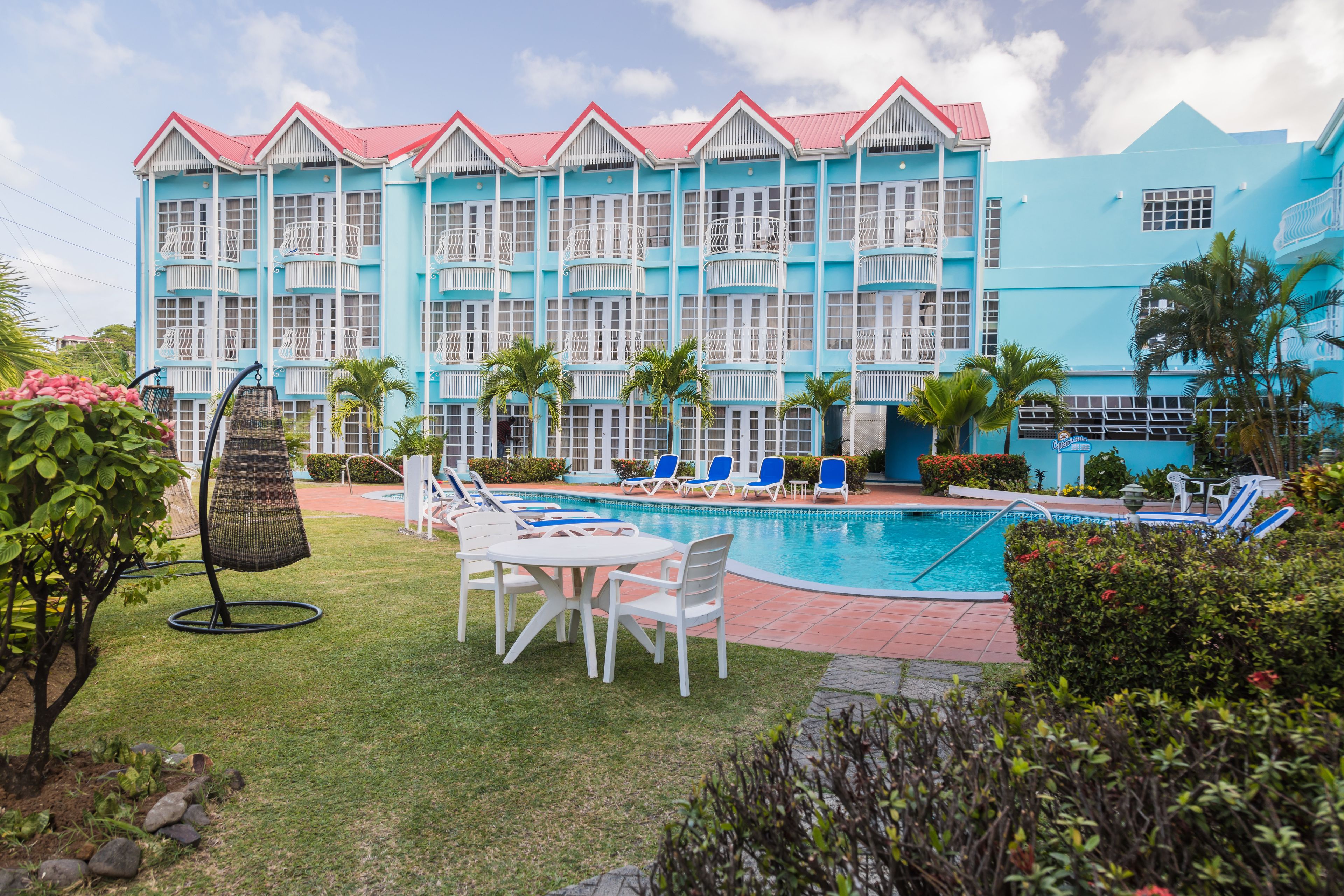 A hotel with a pool area, outdoor seating, and a large building with balconies.