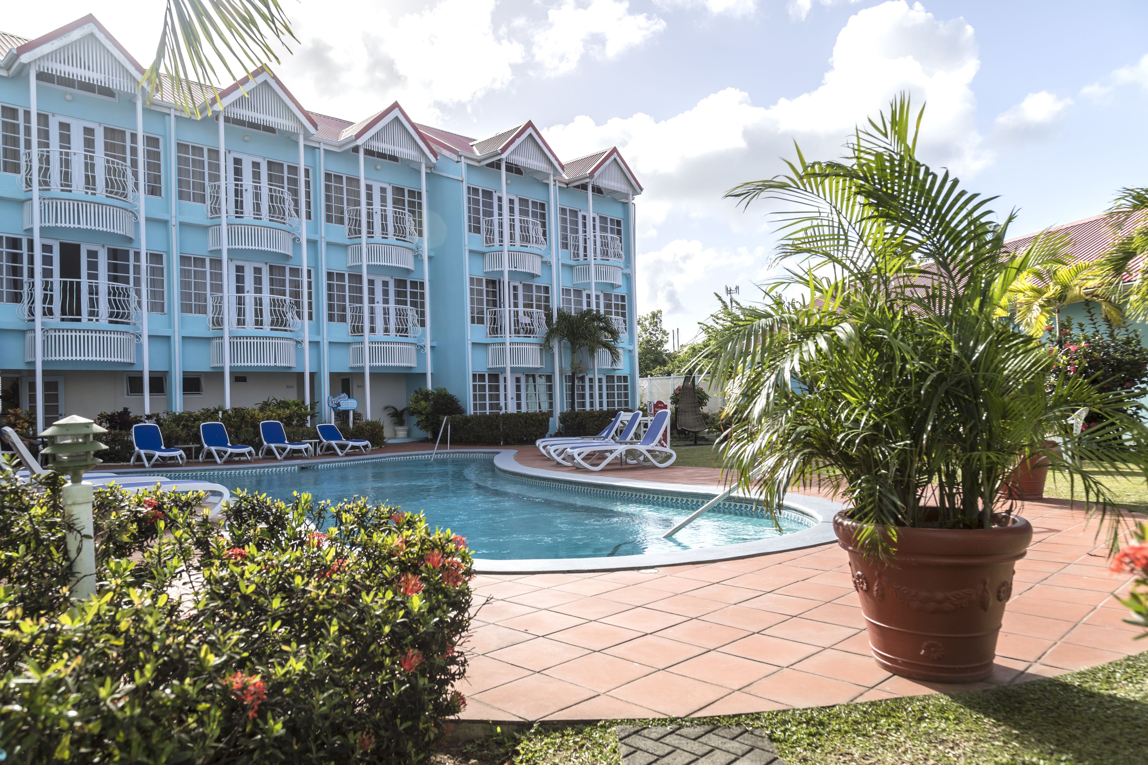 A hotel with a pool, blue exterior, and multiple balconies.