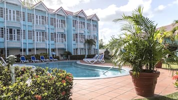 Un hotel con piscina, fachada azul y varios balcones.