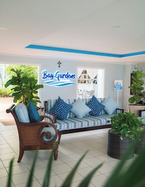 A room with a sofa, a cross on the wall, and a sign that reads 'Bay Gardens.'